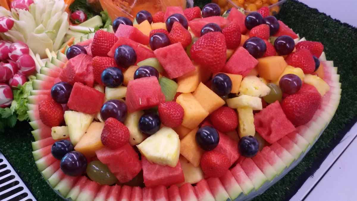 Composizione di frutta in una mezza anguria: anguria, melone, ananas, fragole, mirtilli e uva
