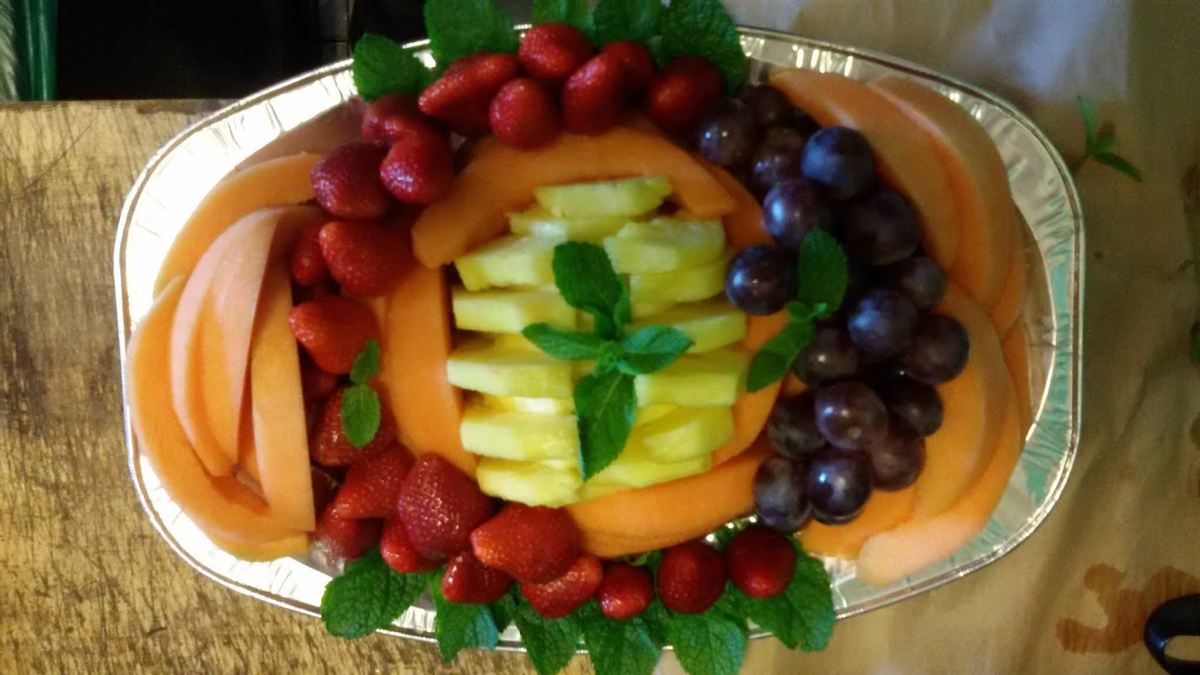 Vassoio di melone, ananas, fragole e uva nera con foglie di menta